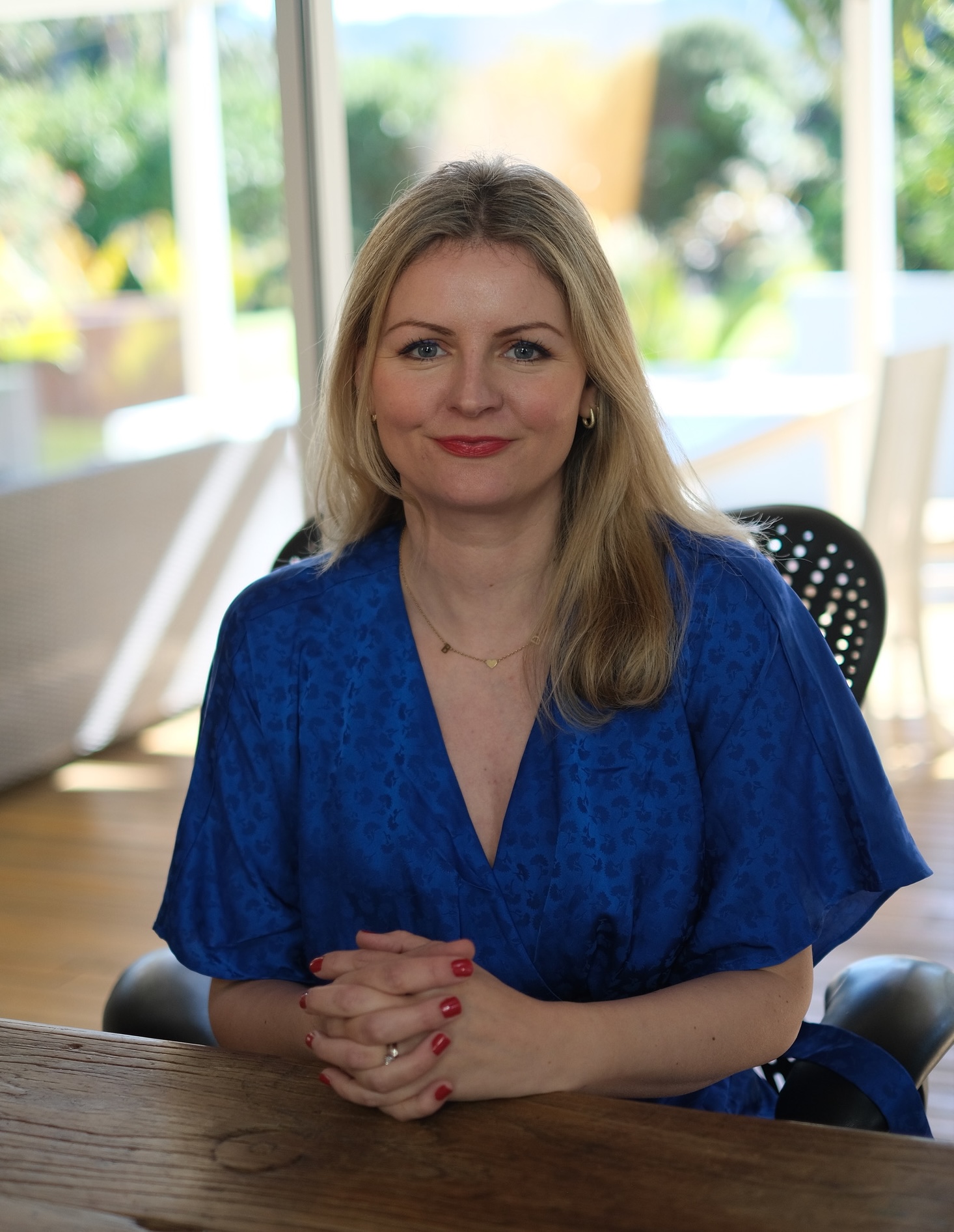 Nina wearing a blue dress, seated at a wooden table